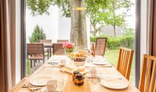 gedeckter Frühstückstisch mit Blick auf die Gartenanlage