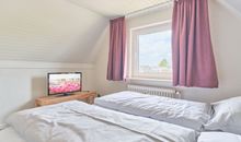 Schlafzimmer mit Doppelbett und TV
