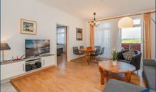 Wohnzimmer mit offener Küche und Zugang zum Balkon