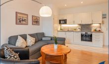 Wohnzimmer mit offener Küche und Zugang zum Balkon