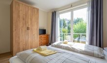 Das erste Schlafzimmer mit Doppelbett und Zugang zur West-Terrasse sowie Kleiderschrank und TV