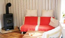Wohnbereich mit Schlafcouch und Kaminofen