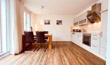 Wohnzimmer mit offener Küche und Zugang zum Balkon