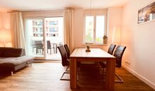 Wohnzimmer mit offener Küche und Zugang zum Balkon